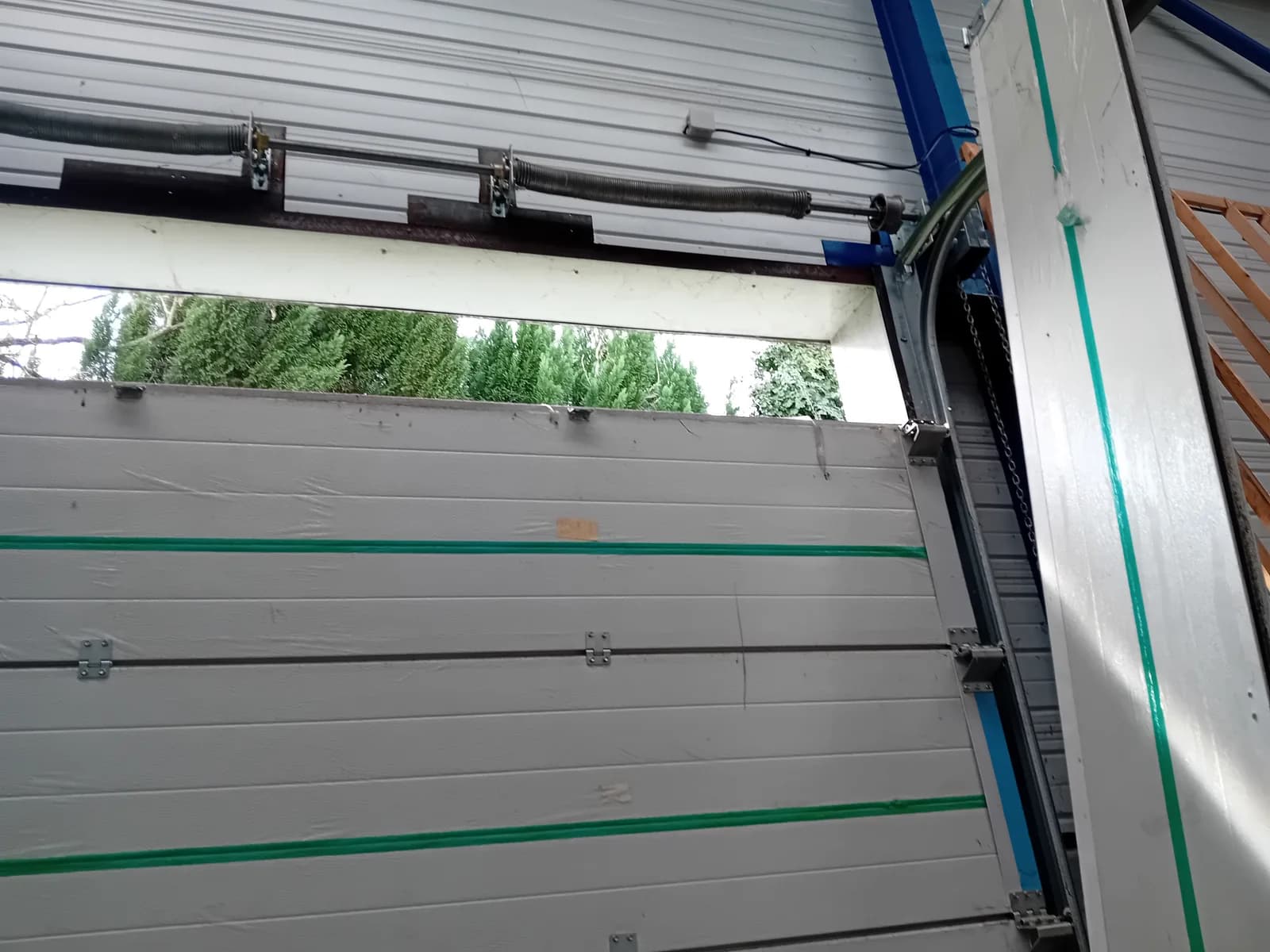 Porte de garage sectionnelle industrielle partiellement ouverte — dépannage et réglage
